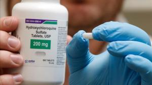 zentauroepp53481276 a pharmacy tech holds a bottle and a pill of hydroxychloroqu200526151024