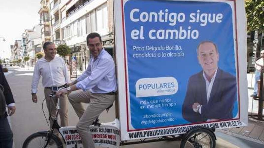 Juanma Moreno pedalea con la publicidad electoral de su candidato en Vélez Málaga a cuestas.