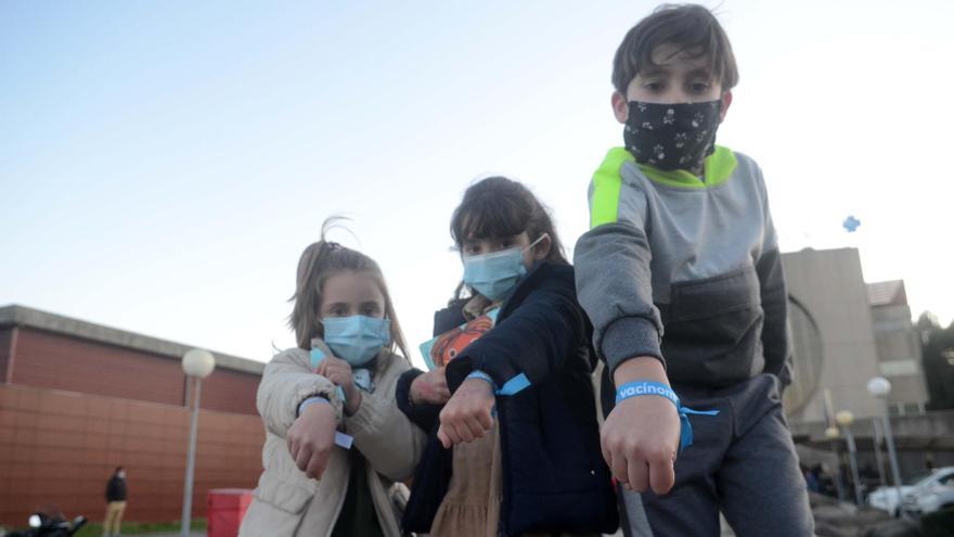 Escolares vacunados ayer muestran las pulseras que les regalaron en el Hospital do Salnés.