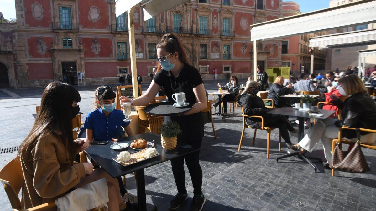 Personas toman algo en una terraza en Belluga.