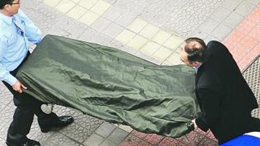 Dos trabajadores de la funeraria trasladan el cuerpo del hombre fallecido, ayer, en Bilbao.