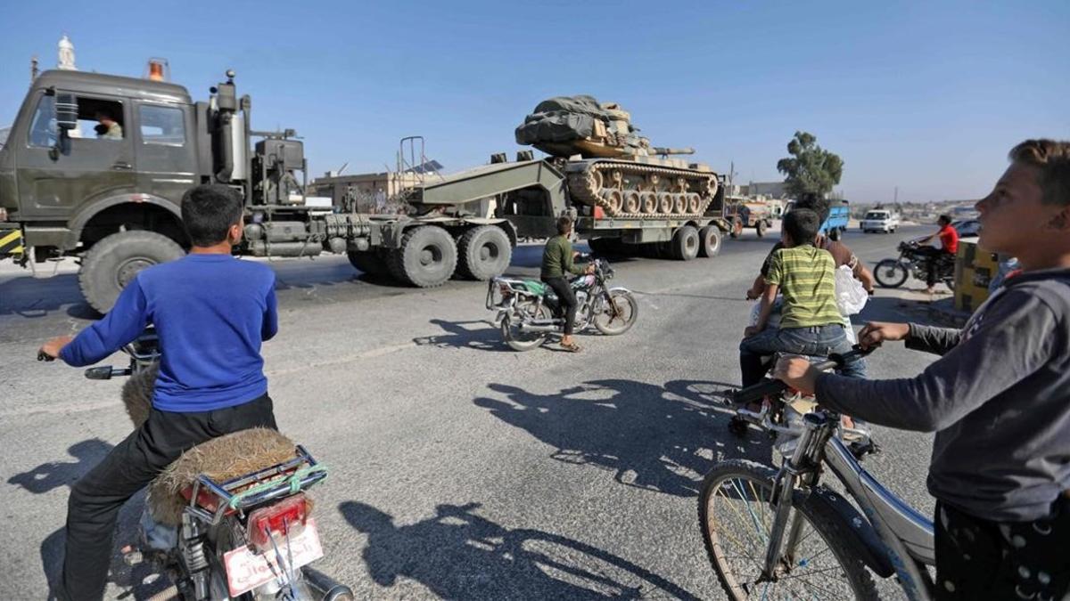 Los niños de Maaret al-Numan, en la provincia de Idlib, en el norte de Siria, observan cómo un vehículo transporta un tanque turco el 19 de agosto de 2019