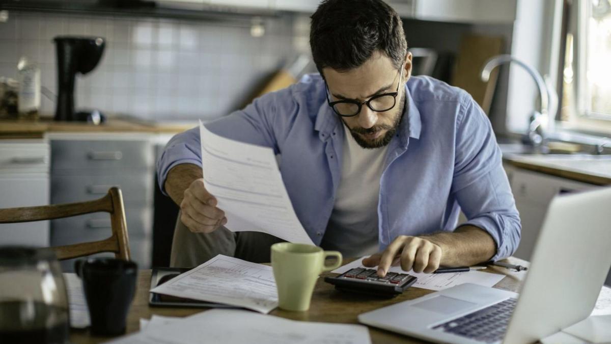 Un home revisa les seves factures amb l’ajuda d’una calculadora. | DIARI DE GIRONA