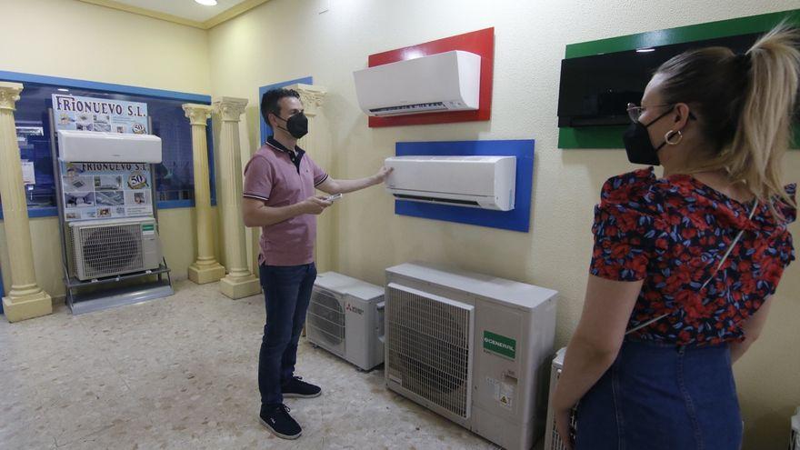 El gerente de Frionuevo, Rafael González, muestra diferentes máquinas de aire acondicionado a una clienta.