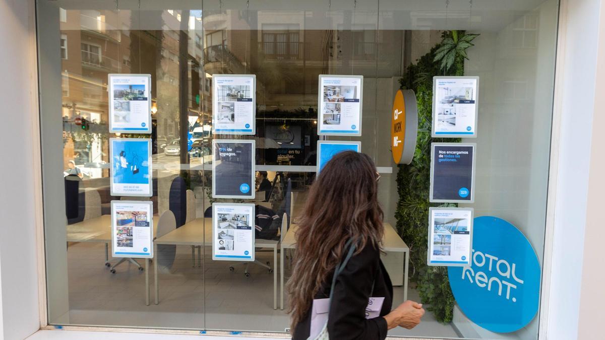Una joven mira pisos en alquiler en una inmobiliaria de Alicante