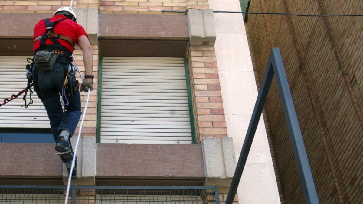 Medidas de seguridad laboral de un trabajador en una fachada.