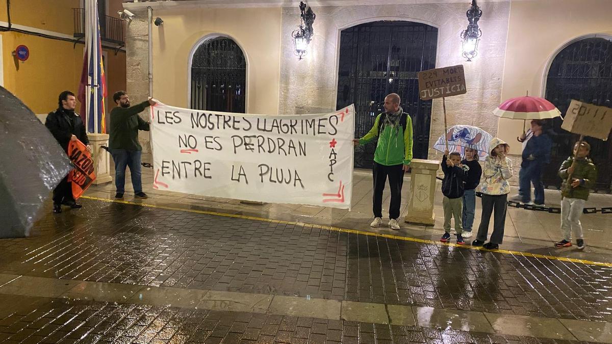 Un reducido grupo de personas protesta bajo la lluvia.