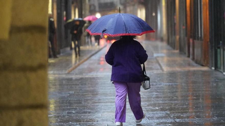 Una dona passejant amb paraigua per Girona. | MARC MARTÍ