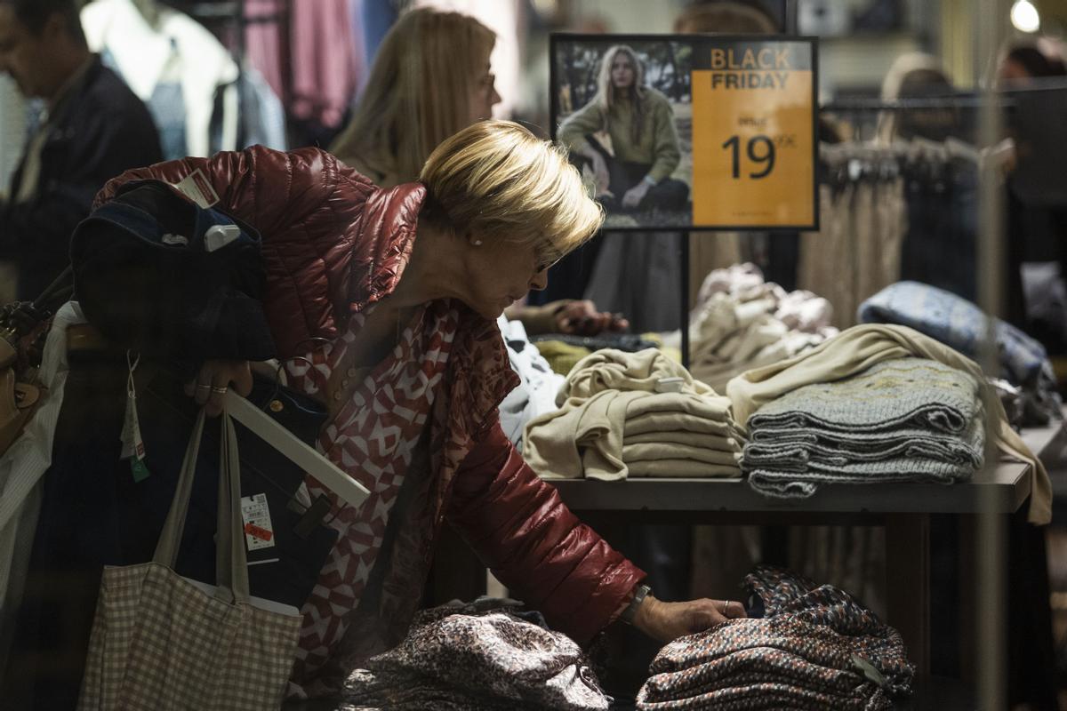 Una mujer toca varios jerséis en una tienda del centro de València.