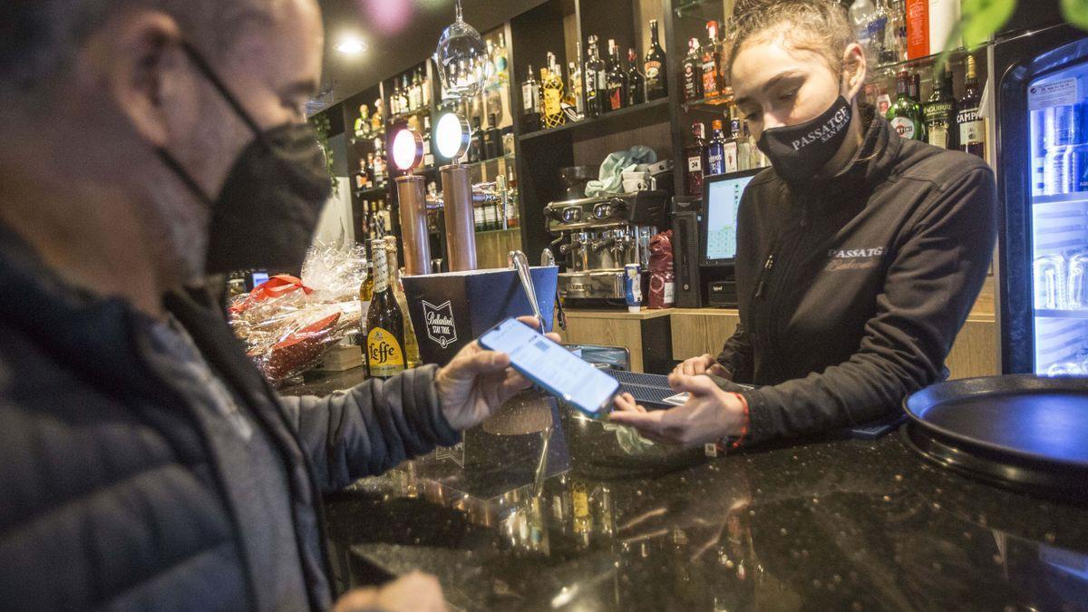 Un cliente de un bar muestra su pasaporte covid en la Comunidad Valenciana.