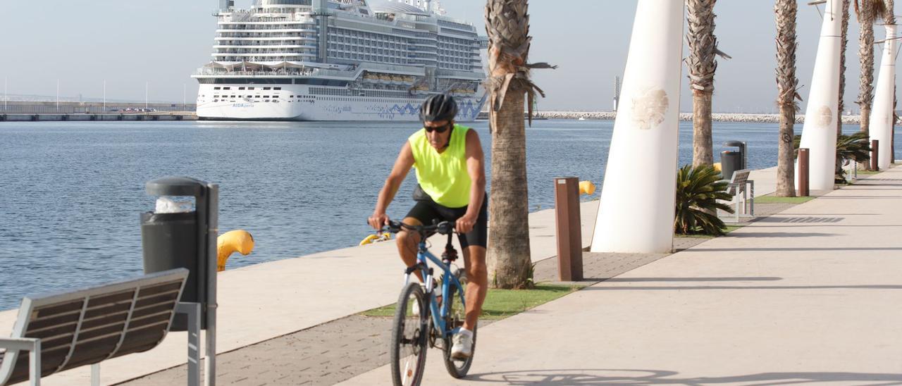 Un ciclista hacer deporte por el paseo del puerto esta mañana. Al fondo, un crucero haciendo escala