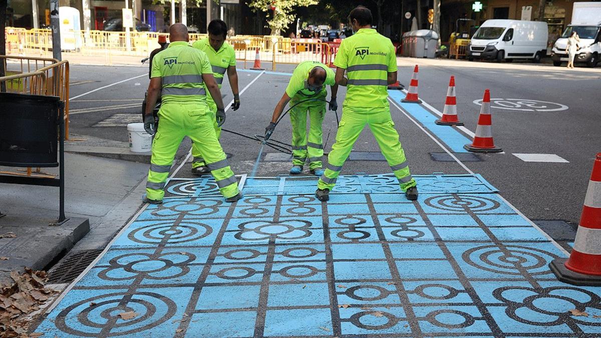 Un grupo de operarios pintan parte de la calzada de la calle de Rocafort de Barcelona para ampliar el espacio destinado a los peatones, el pasado 2 de julio