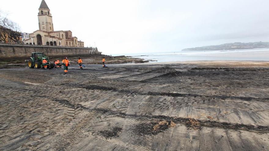 Operarios de Emulsa limpian de carbón la playa de San Lorenzo, el pasado mes de febrero.