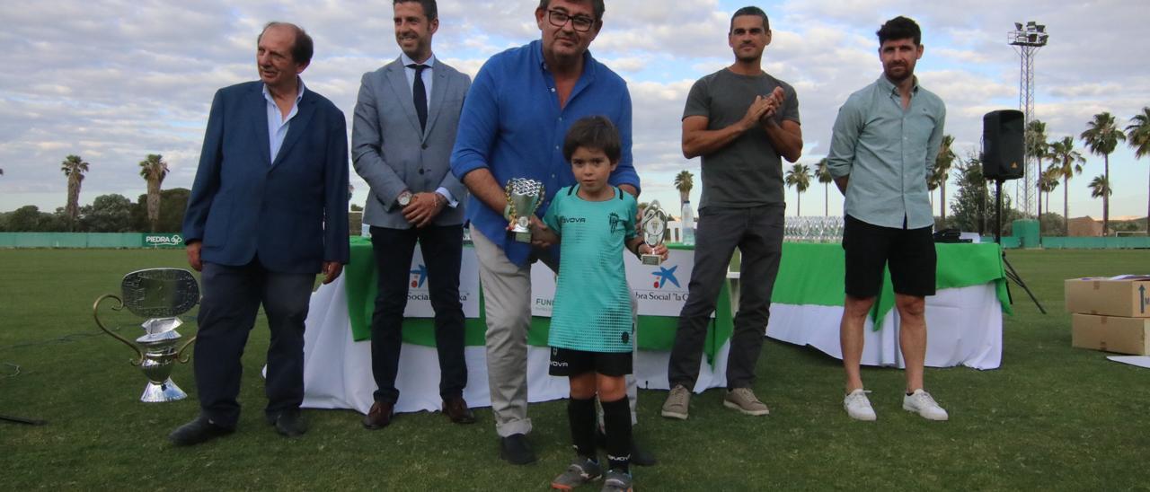 González Calvo, en el centro, tras entregar un trofeo a uno de los niños del fútbol base del Córdoba CF.