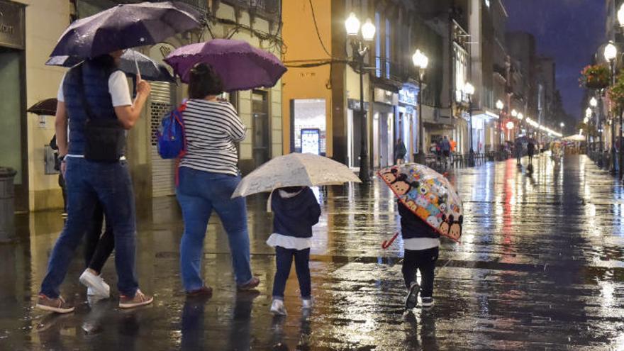 Una familia se cubre de la lluvia en la calle Triana