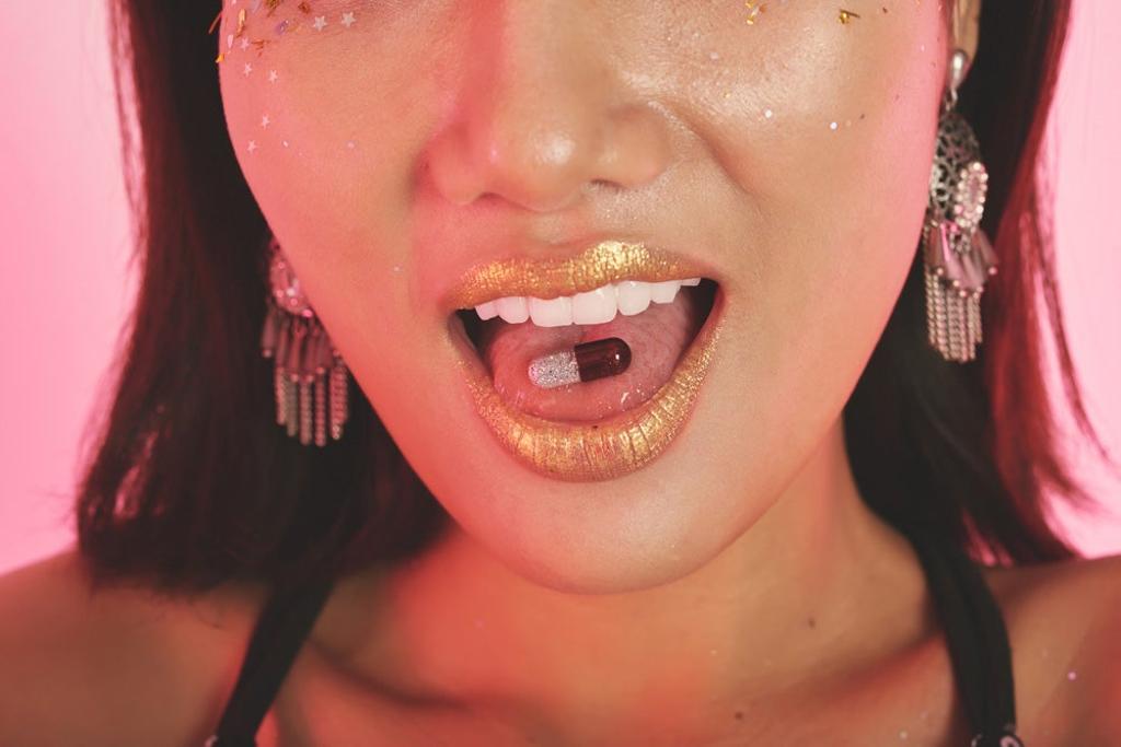Chica con pastilla de purpurina en la boca