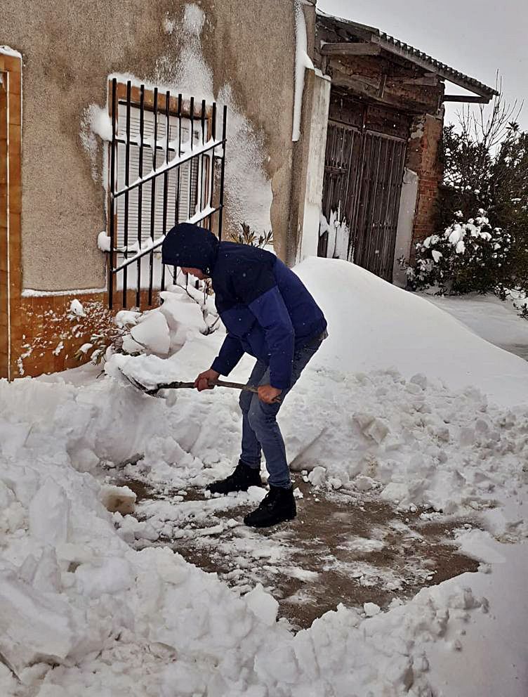 Un vecino de El Pego retira la nieve acumulada junto a una vivienda.
