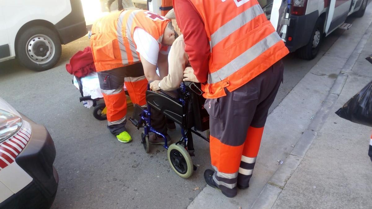 Un hombre en silla de ruedas es trasladado por la Cruz Roja.