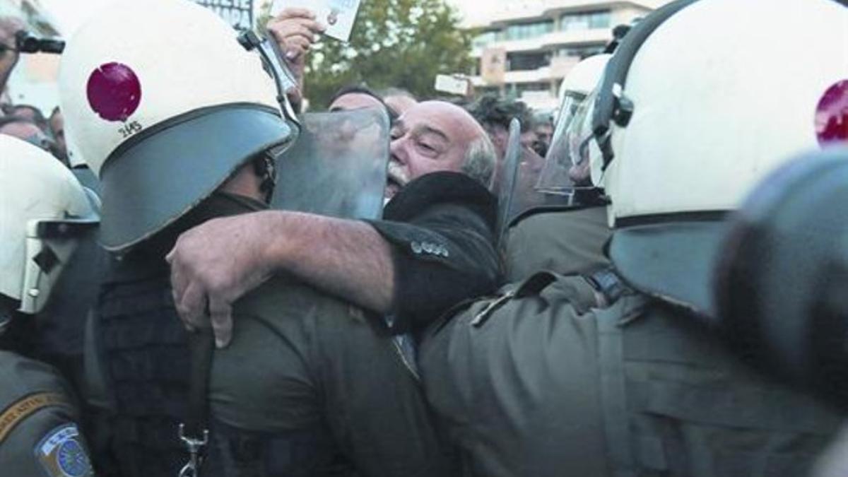 La protesta 8Un parlamentario de Syriza forcejea con la policía frente a la sede central de la radiotelevisión griega, ayer.