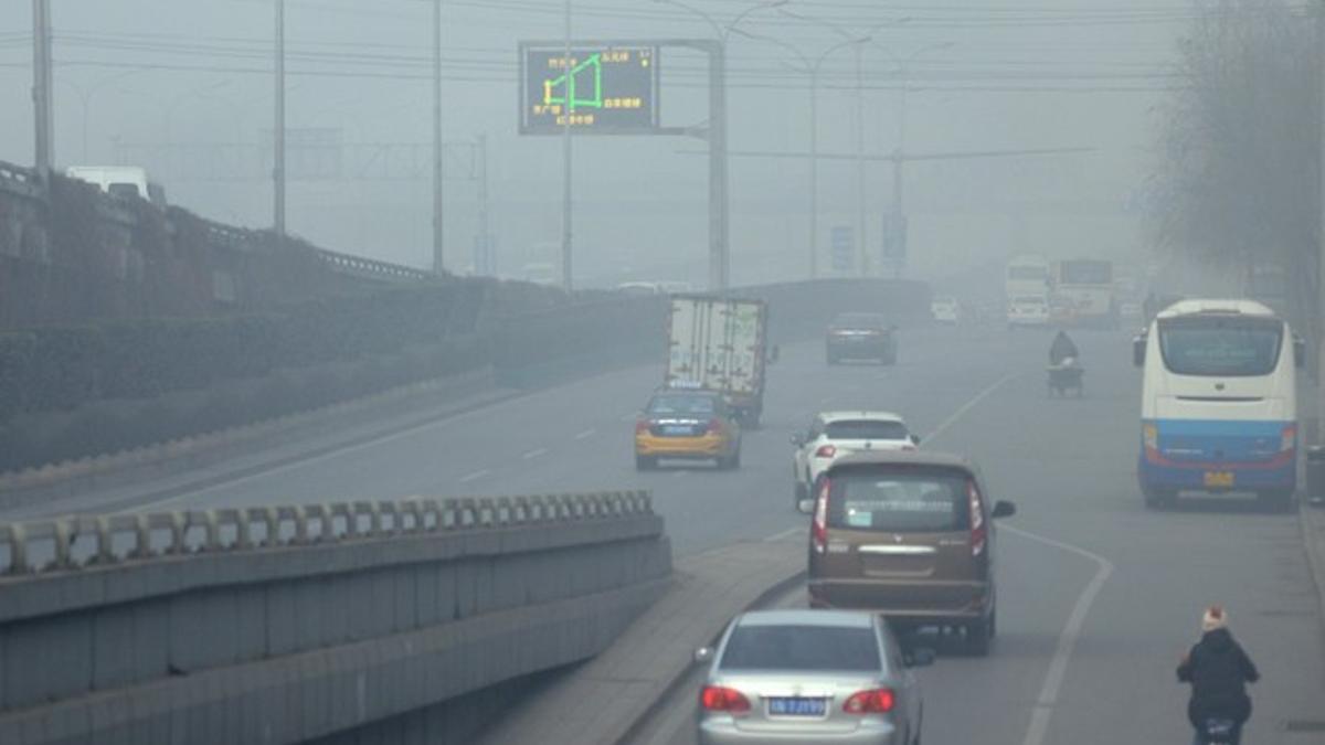 Varios vehículos circulan por una carretera llena de polución, este viernes, en Pekín.
