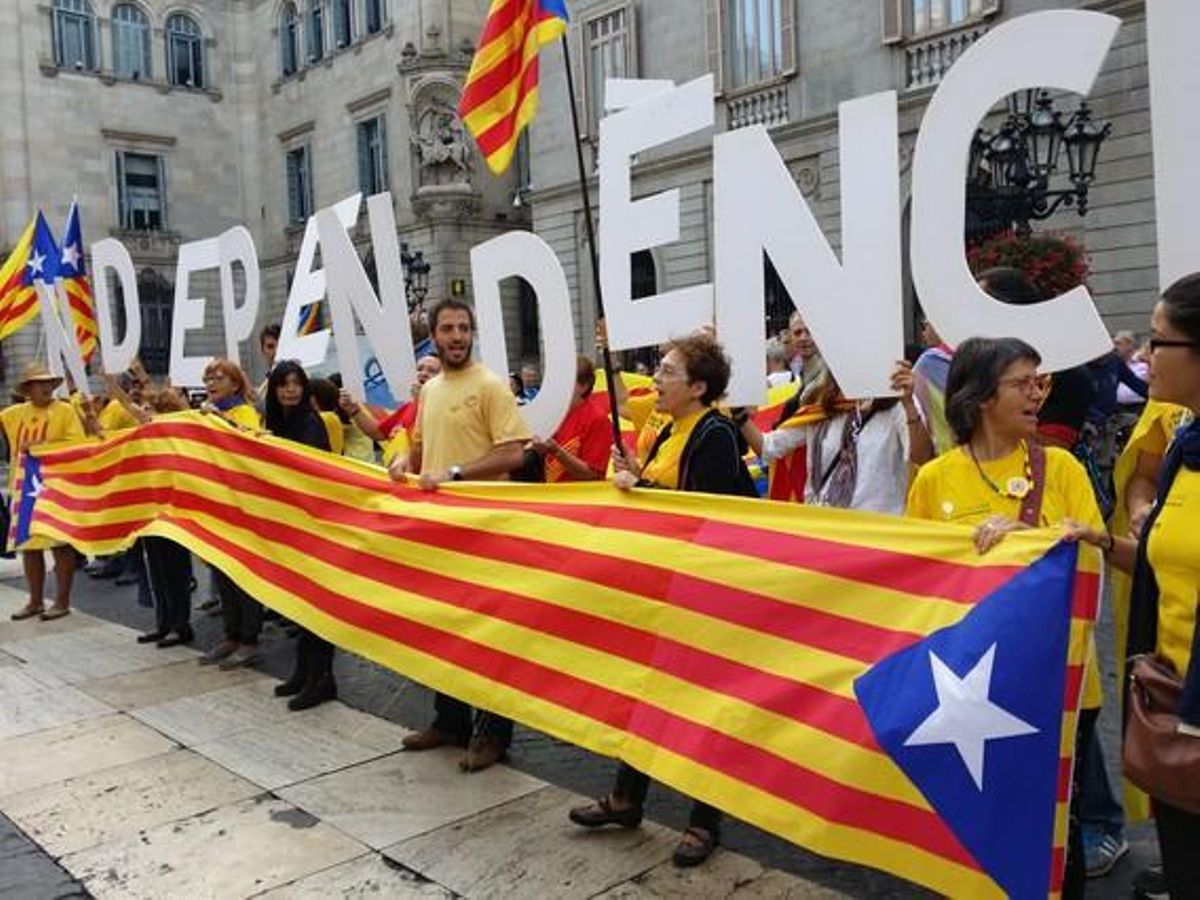 Simpatitzants de l’ANC i Òmnium Cultural, darrera una senyera, a la plaça Sant Jaume, aquest dissabte.