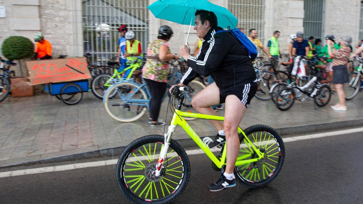 Un ciclista sostiene un paraguas en Alicante este sábado.