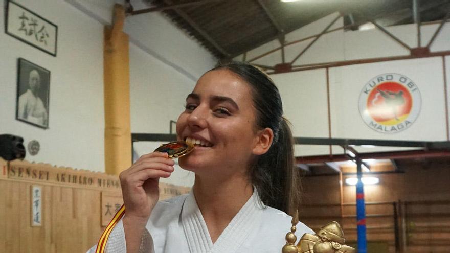 La karateca, Sara García muerde el oro obtenido recientemente mientras sujeta el trofeo de campeona de España en su categoría.