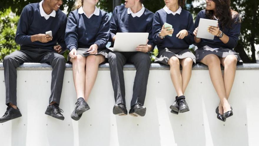 Estudiantes con teléfonos móviles y otros dispositivos.