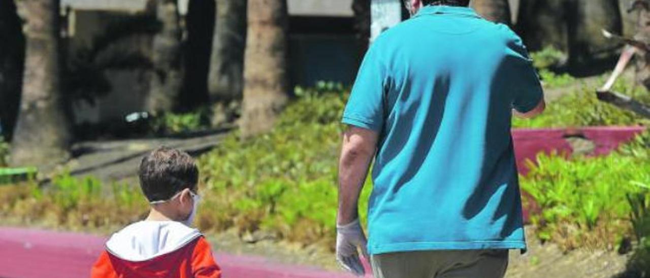 Un niño pasea por la calle, acompañado de un adulto.