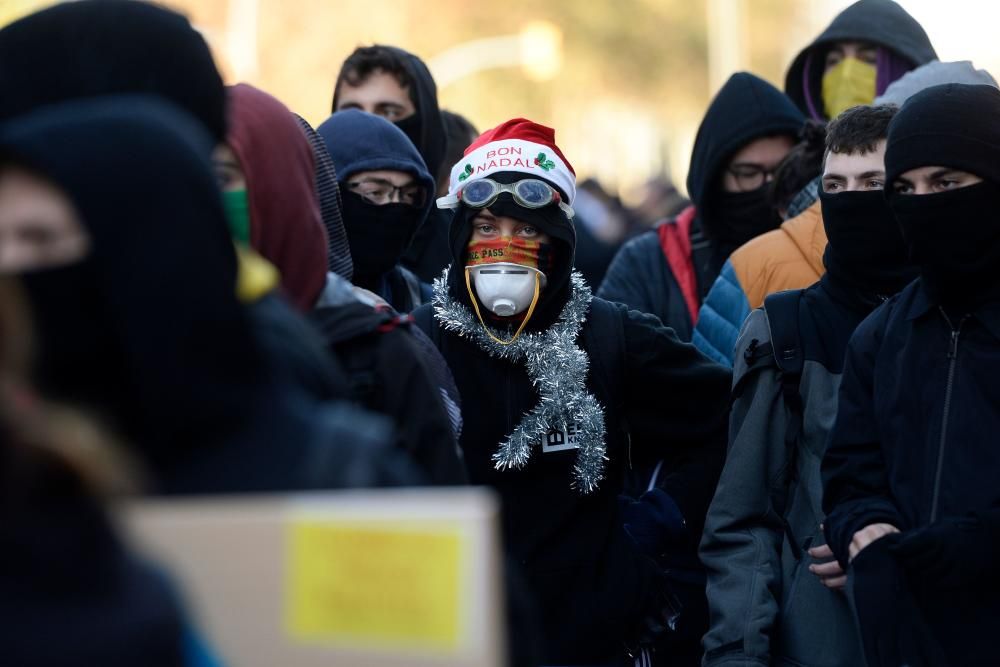 TOPSHOT - A protester wearing a Santa hat and a tinsel around the neck stands with fellow Catalan pro-independence demonstrators during a protest in Barcelona on December 21, 2018 as the Spanish cabinet held a meeting in the city. - The meeting comes a year to the day after Madrid held snap elections in Catalonia after blocking the wealthy northeastern region's move for independence and many separatists have called the timing of the meeting "a provocation". (Photo by Josep LAGO / AFP)