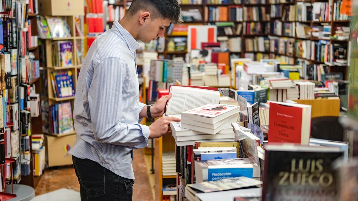 Un joven consulta un libro de lectura en la casa del libro de Badajoz.