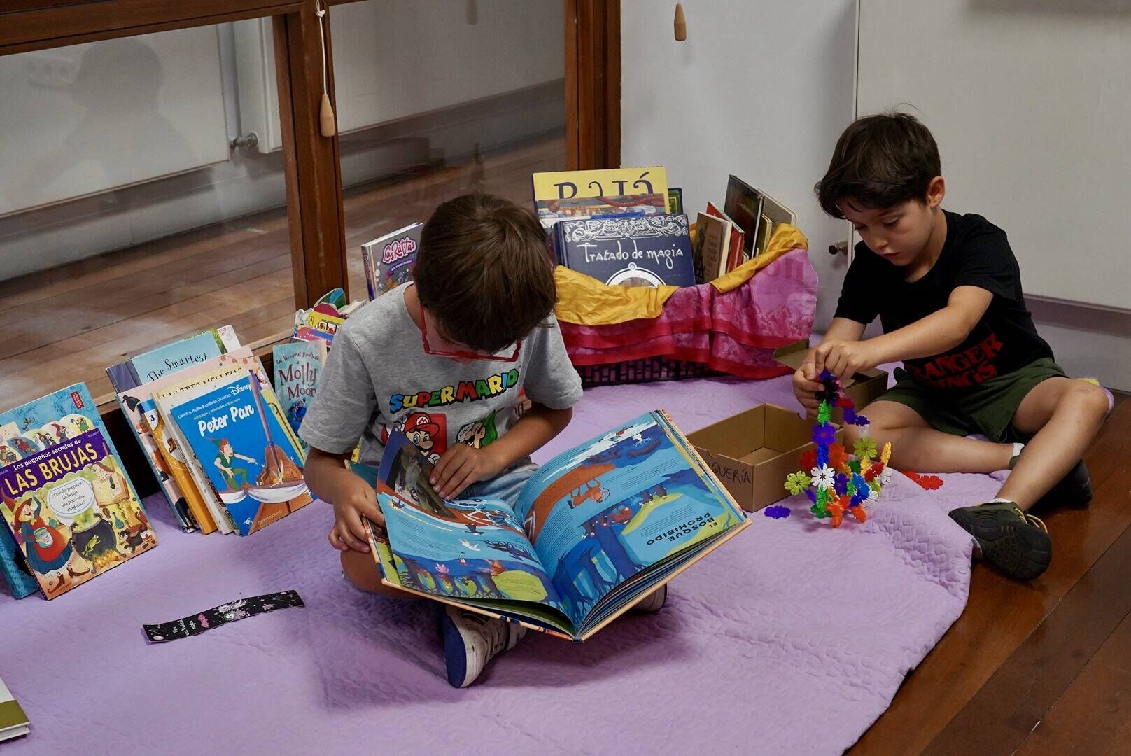 Dos niños leen y juegan durante el taller.