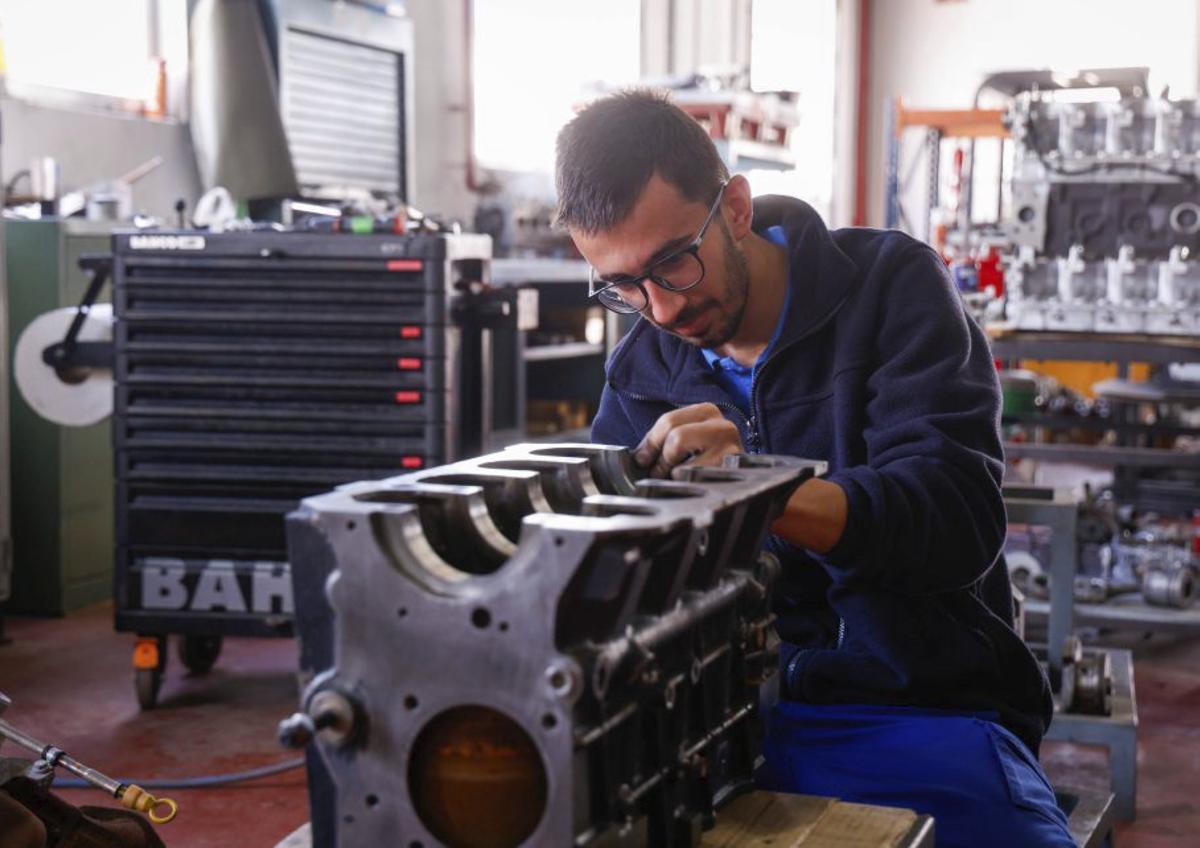 Un trabajador inspecciona un motor de vehículo.