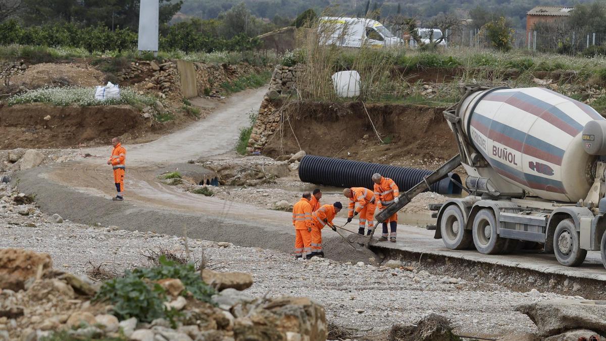 Operarios trabajando en la reconstrucción de un paso sobre el barranco del Pozalet en Cheste, en una obra financiada por la Diputación de València.