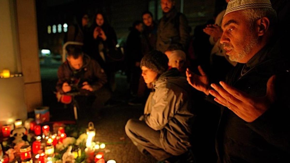 Un grupo reza frente a un altar con velas encendidas en memoria del niño inmigrante asesinado.