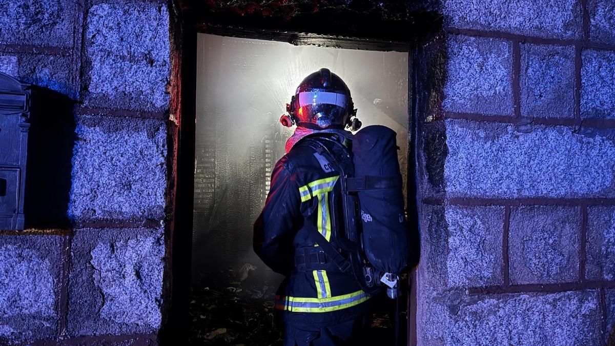 Un bombero en la extinción del incendio de una vivienda en un municipio de Madrid.