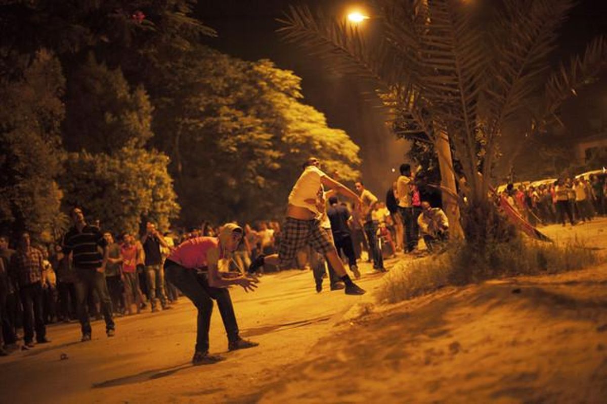 Manifestants anti-Mursi llancen pedres contra una seu dels Germans Musulmans, en un barri del Caire.