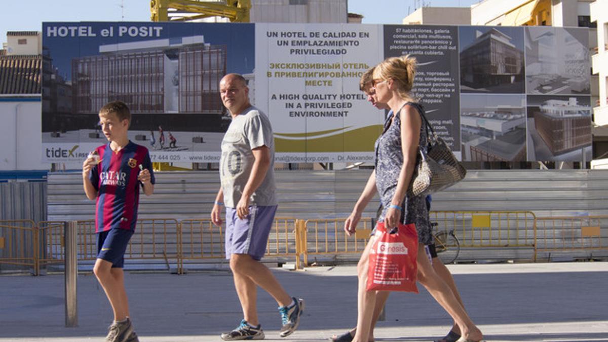 Turistas rusos pasan delante de un hotel en construcción en Cambrils.