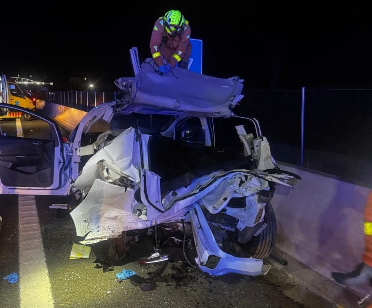 Un bombero tras levantar el techo del vehículo en el que quedaron atrapadas las víctimas del accidente de la V-21, en la Pobla de Farnals.