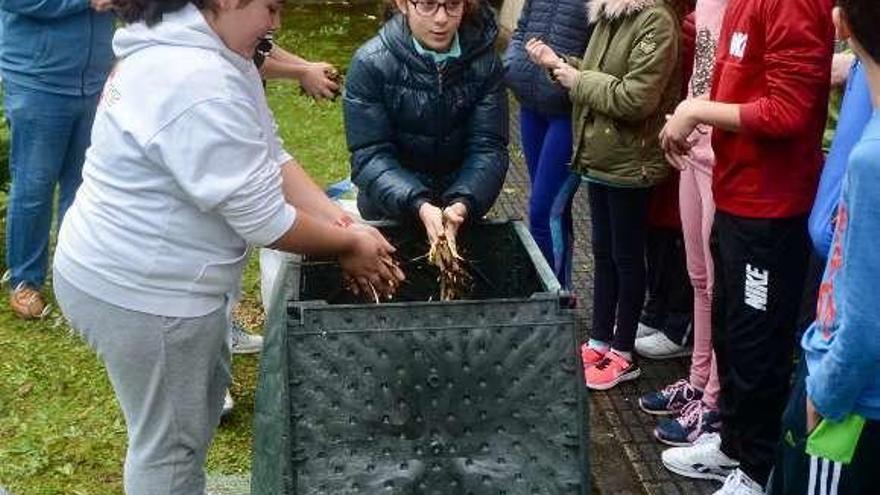 Unas niñas aprenden a usar un compostero en Monte Porreiro. // R.V.