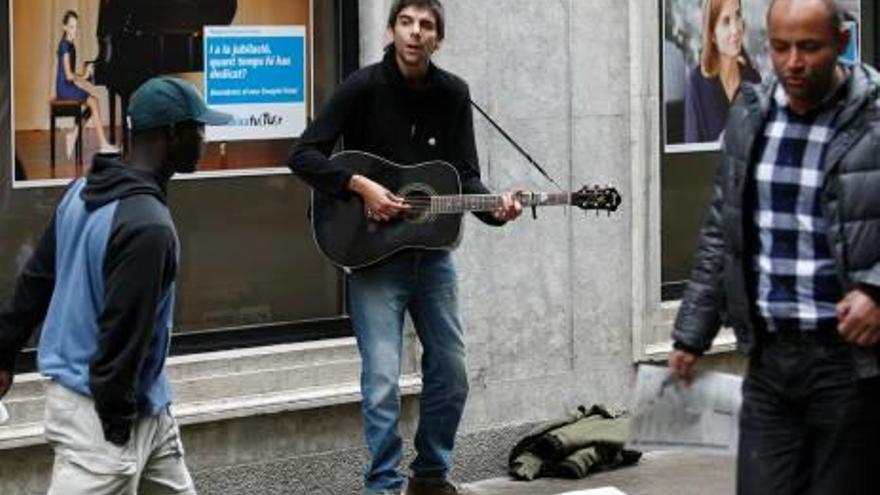Un músic de carrer tocant al carrer Nou de Girona.
