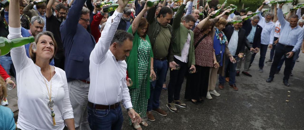 Arriba, por la izquieda, Sandra Vigón (alcaldesa de Colunga), Juan Cañal (alcalde de Nava), Guillermo Guisasola (presidente del consejo regulador de la denominación de origen), la directora general Begoña López, Alejando Vega (alcalde de Villaviciosa), José Luis Almeida (presidente de Otea), Gimena Llamedo ( vicecretaria de la FSA), y Mariví Monteserín (alcaldesa de Avilés), entre otros, durante el escanciado delante del Museo de la Sidra. A la izquierda, Felgueres y Mario Arias, con Pablo Onís, del PP de Nava. | L. Murias |  FIRMA