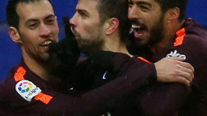 Busquets y Suárez abrazan a Piqué tras su gol.