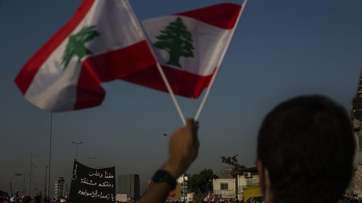 UIn hombre sostiene dos banderas de Líbano en una imagen de archivo.