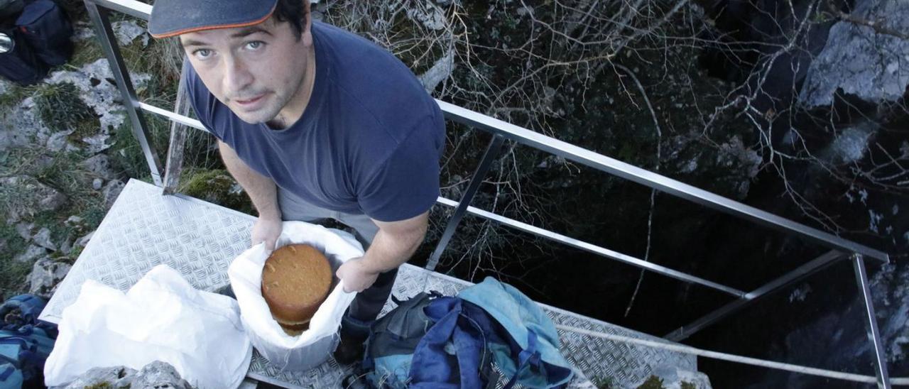 Enrique Remis hijo, con un queso, a la entrada de la cueva donde elaboran las piezas. | Ángel González