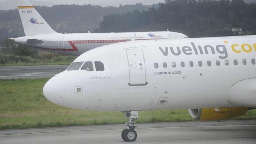 Un avión de Vueling Airlines, en primer plano, en la pista del aeropuerto de Alvedro. / carlos pardellas