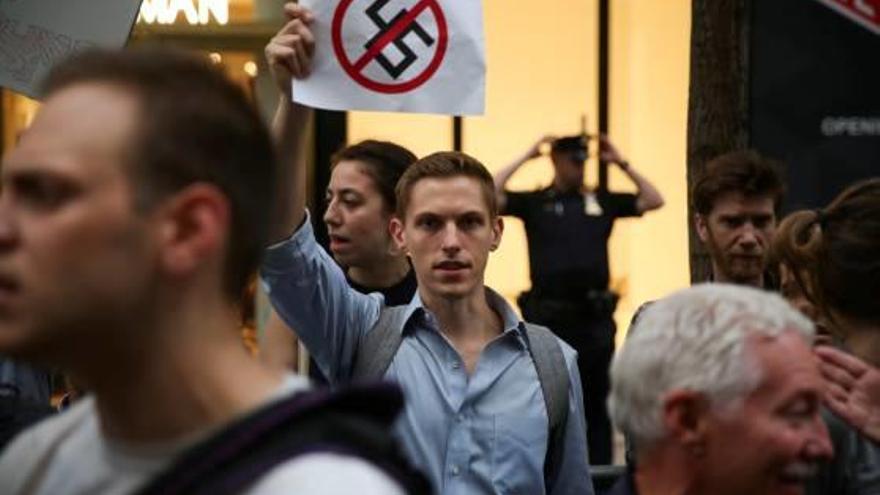 Un participant en una protesta contra Trump i el nazisme mostra una pancarta.