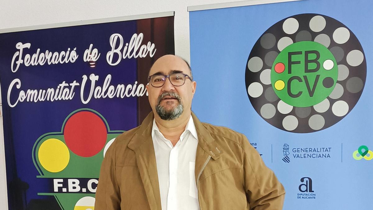 Javier Muñoz entre los logos de antes y actual de la Federación de Billar de la Comunitat Valenciana