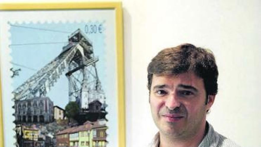 Fermín Santos posa frente al sello donde representa la localidad de Mieres.