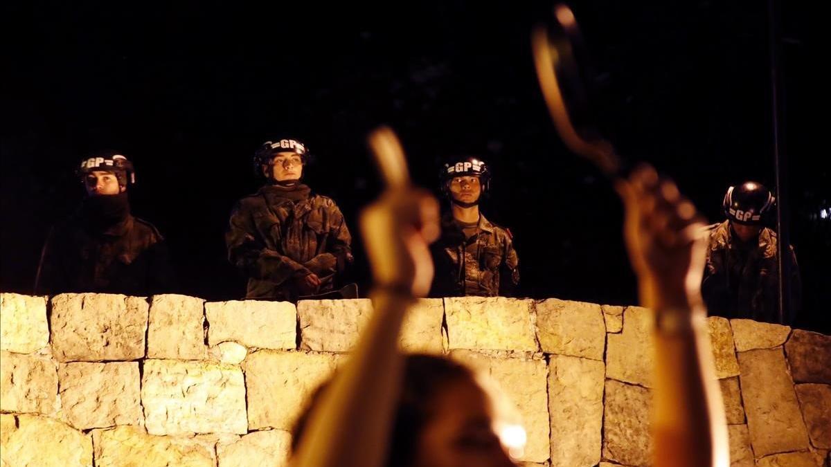 Soldados vigilan a manifestantes que golpean sartenes y cazuelas en una protesta frente a la residencia privada del presidente colombiano, Iván Duque, en Bogotá.